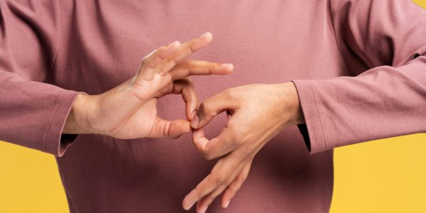 Close up of man showing word INTERPRETER in sign language, isolated on yellow background. People lifestyle concept