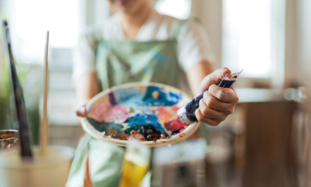 Close up of a creativity young woman artists hands painting vibrant strokes on a canvas in artistic process in workshop.