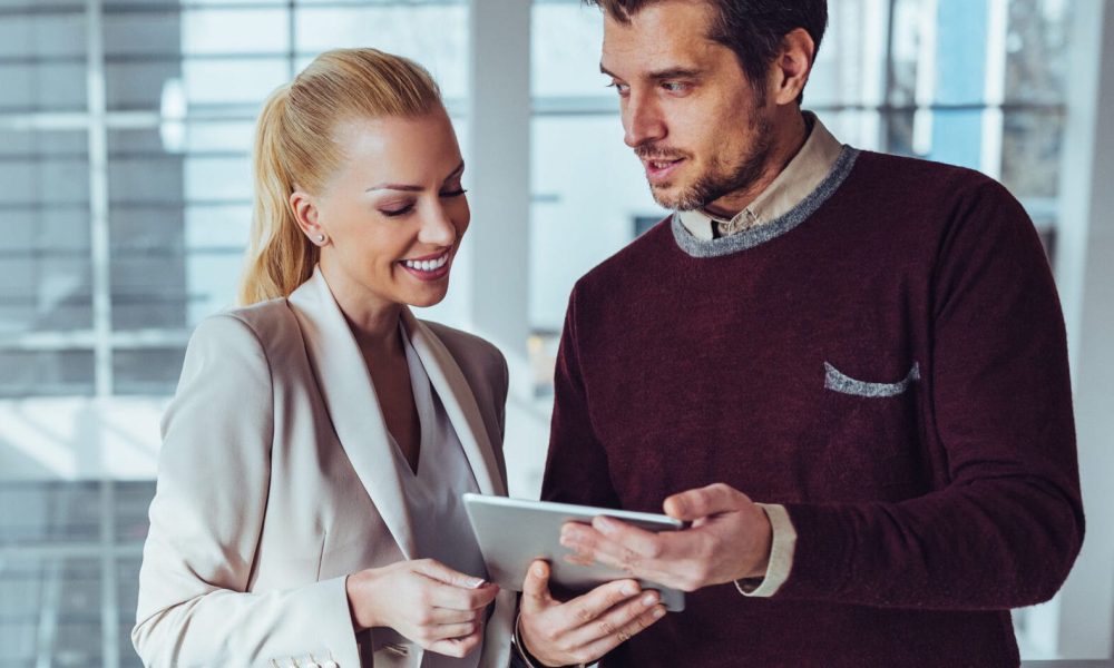 Two business colleagues standing with a digital tablet and discussing about work