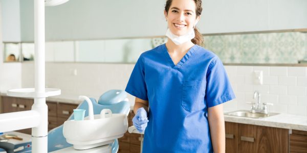 Portrait of smiling female dentist wearing scrubs while standing at clinic