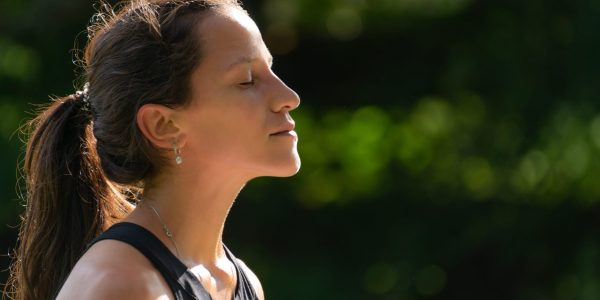 Side View of Young Woman Face Breathing and Enjoying the Sun Against Green Nature Background