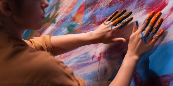 Woman painting with fingers on canvas in art studio.