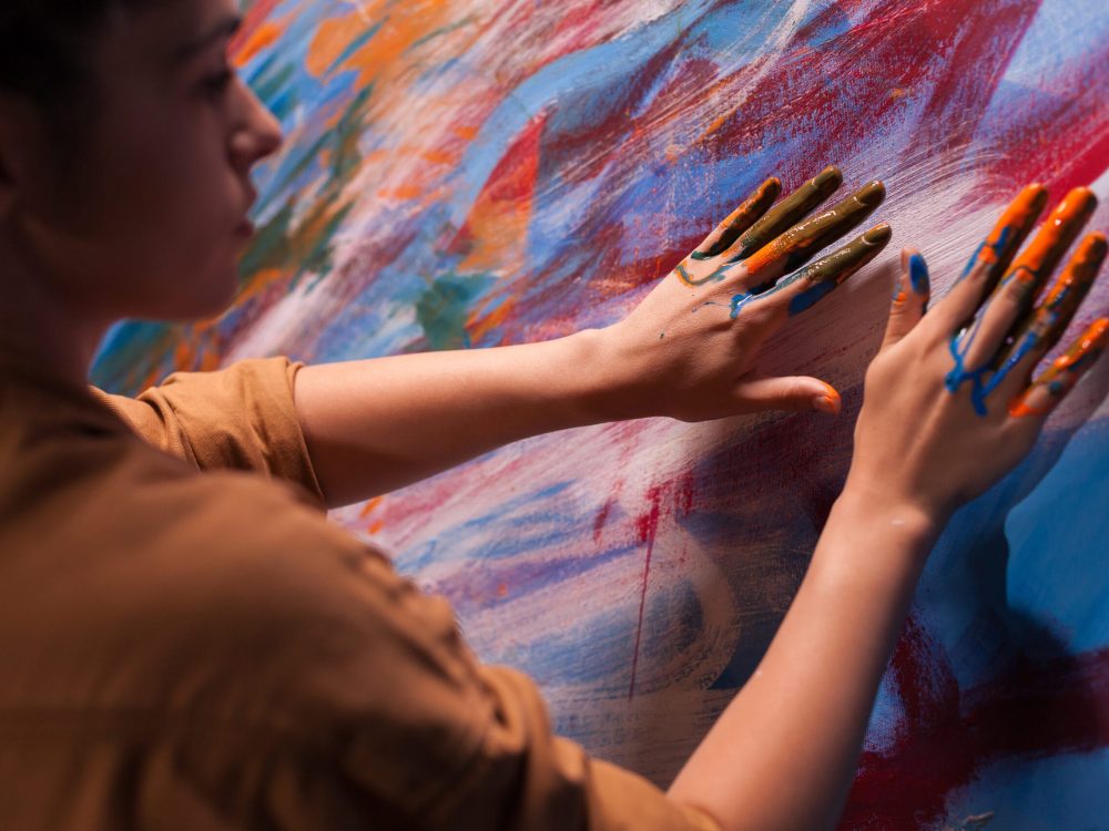 Woman painting with fingers on canvas in art studio.